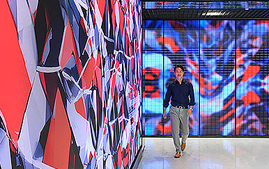 A person walking in a room with a wall of flags.