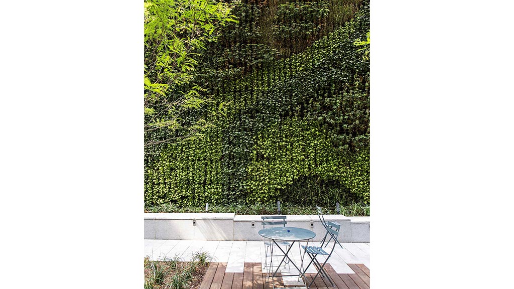 A pool with a table and chairs on a deck with trees in the background.