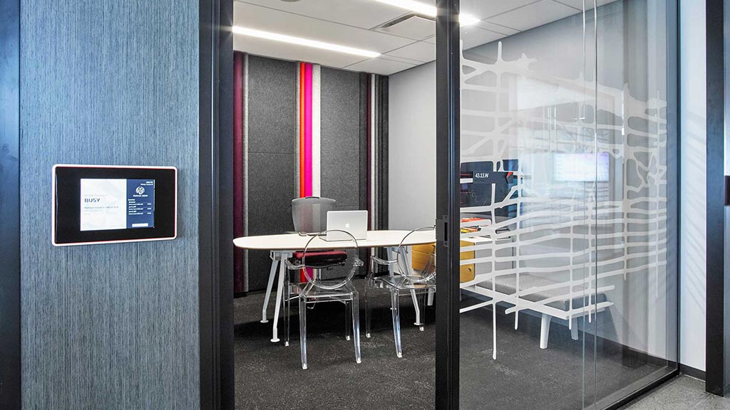 A room with a glass door and a table with chairs and a sign.