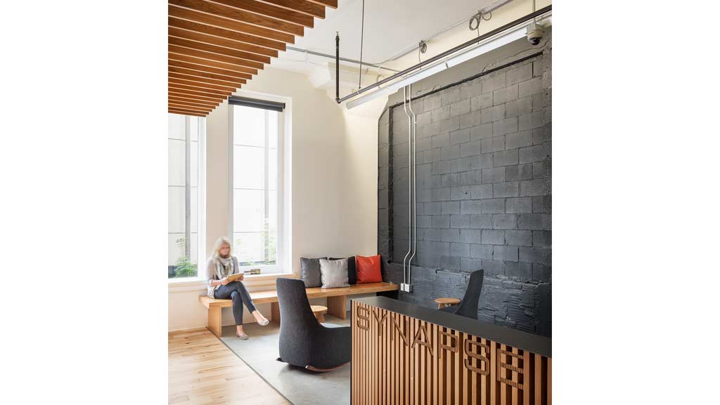 A person sitting on a chair in a room with a brick wall.