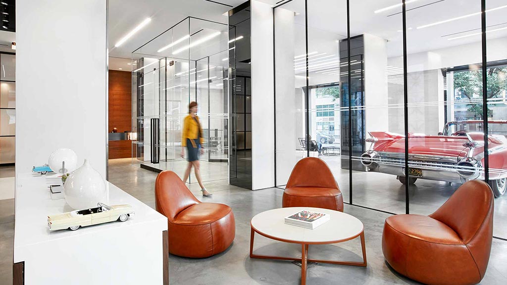 A person walking in a room with a glass wall and a table.