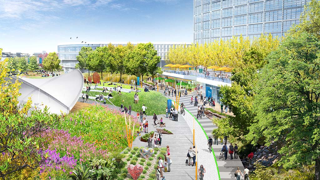 A group of people walking around a park with trees and buildings in the background.