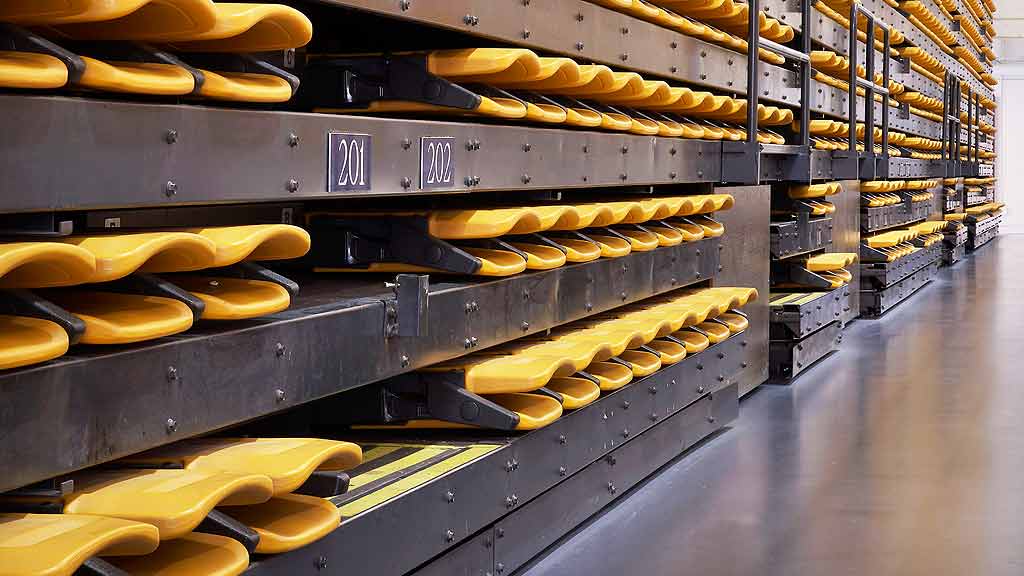A row of yellow and white hotdogs on a conveyor belt.
