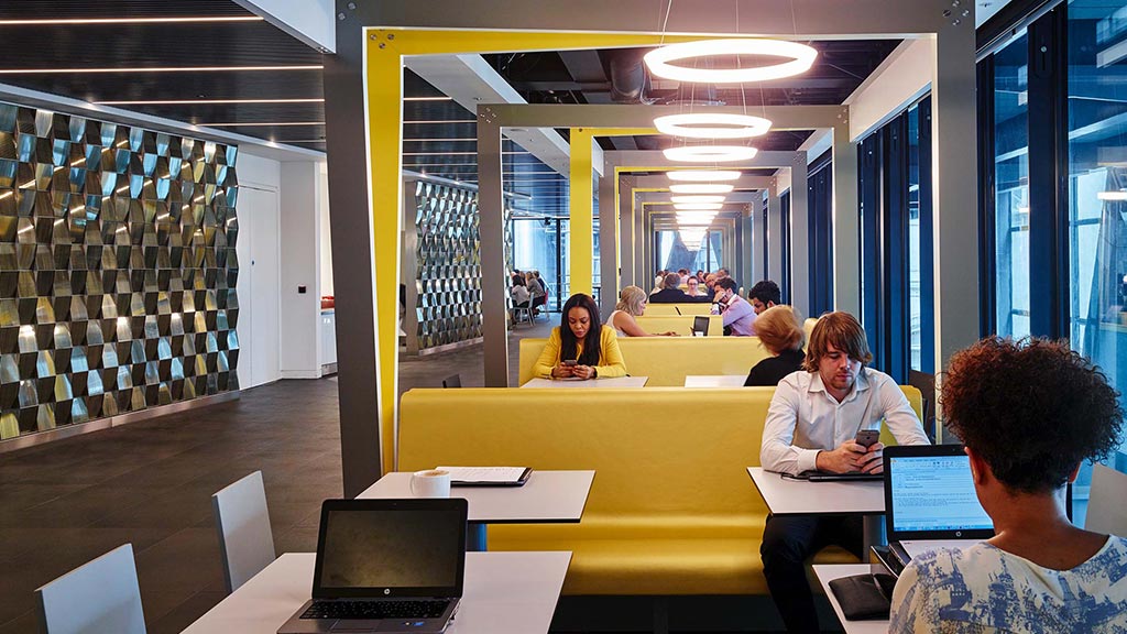 A group of people sitting at a table with laptops.