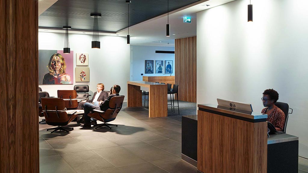 A couple of people sitting in a room with a large screen.