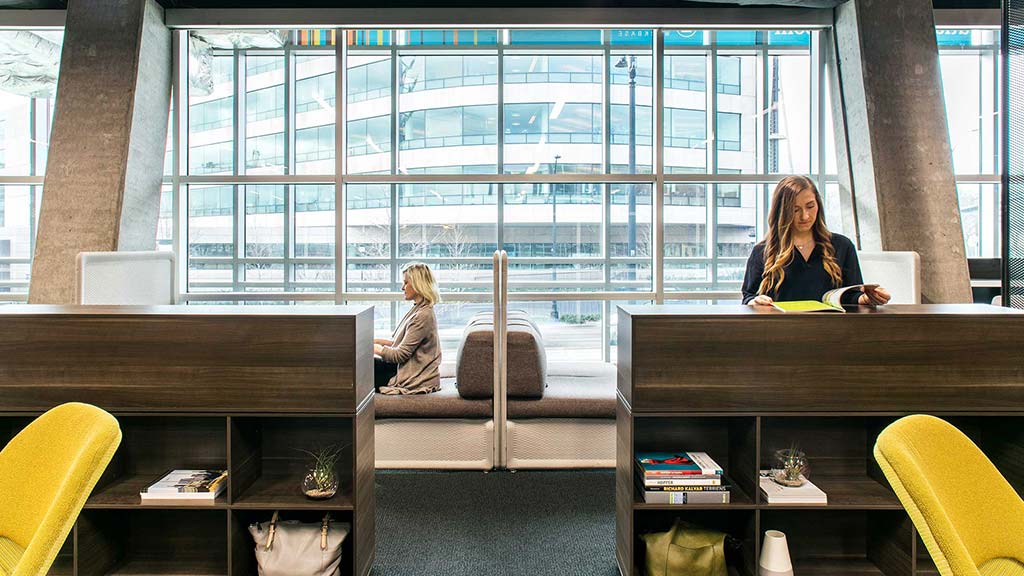 A person sitting at a desk in a room with a large window.