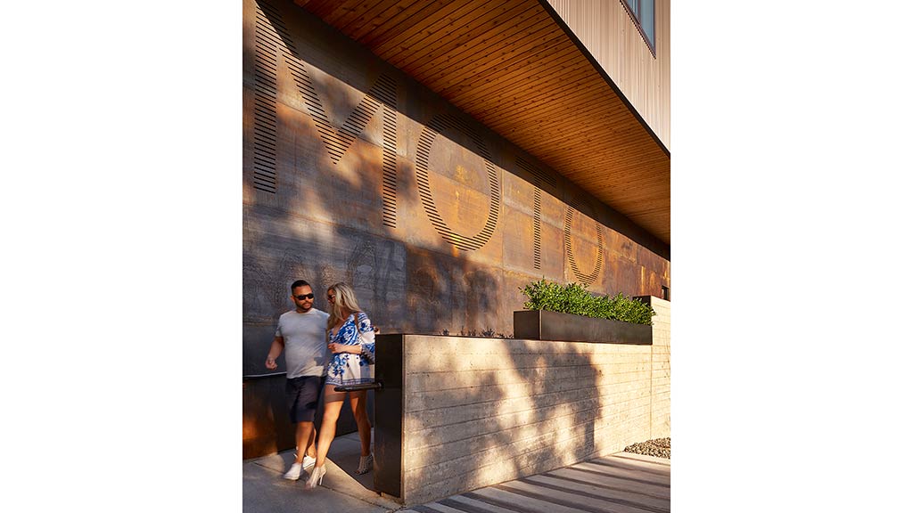 A man and a woman standing in front of a wall with a design.