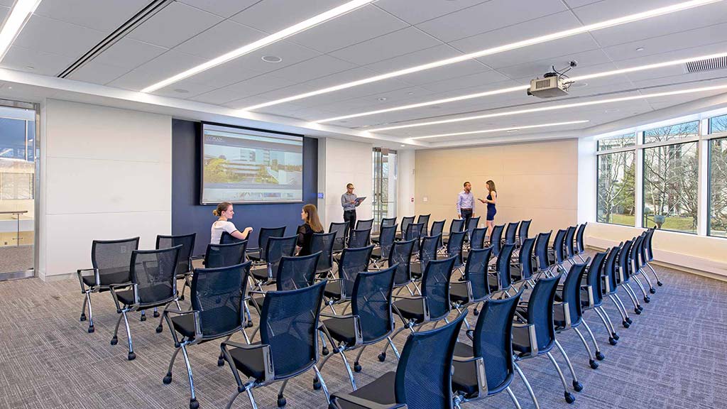 A room with rows of chairs and a projector screen.