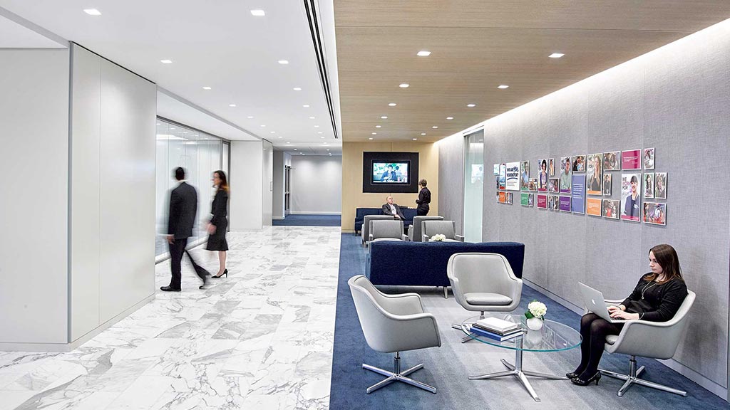 A person sitting in a chair in a room with a tv and people.