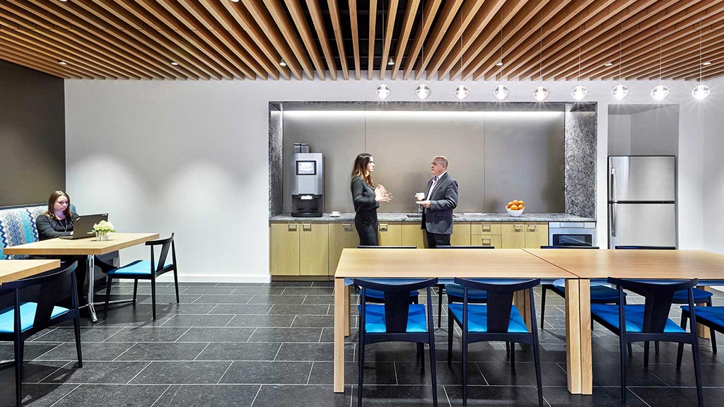 A man and woman standing in a room with tables and chairs.