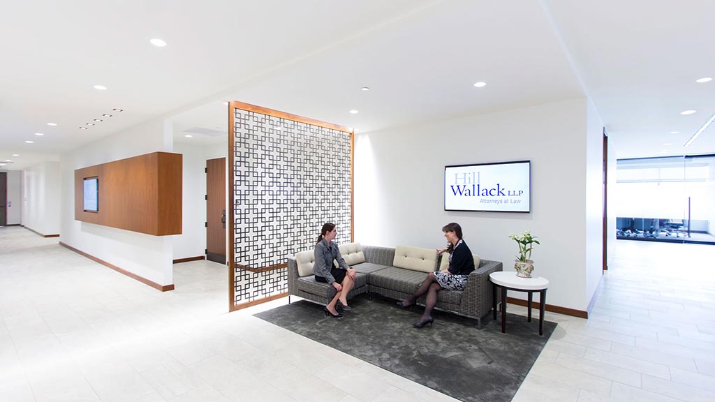 A couple of women sitting on a couch in a room with a tv.