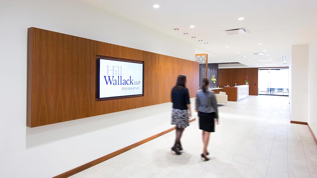 A couple of women looking at a screen in a room with wood walls.