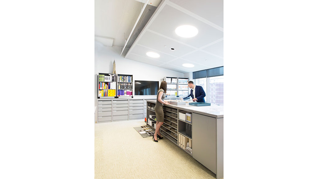 A woman standing in front of a counter with a man sitting at it.