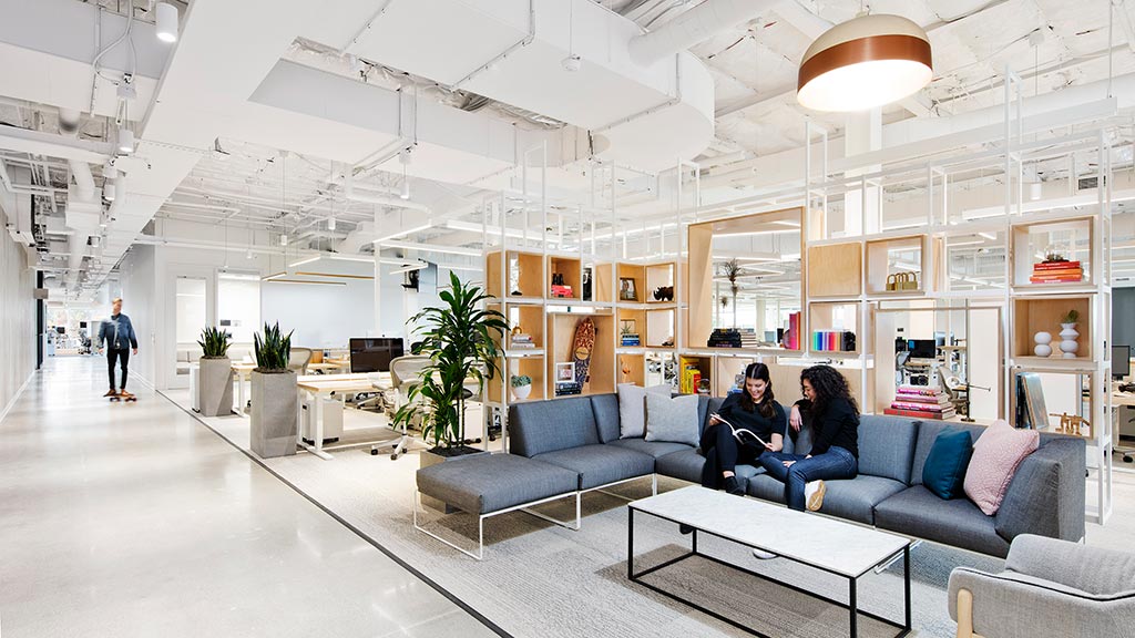 A room with a few people and a couch and a coffee table.