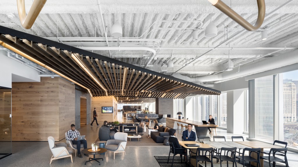 A group of people sitting at tables in a large room with a large ceiling.