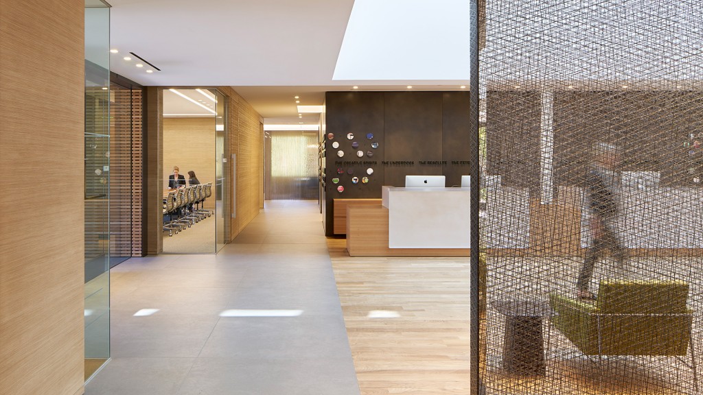 A room with glass walls and a white table with a laptop on it.