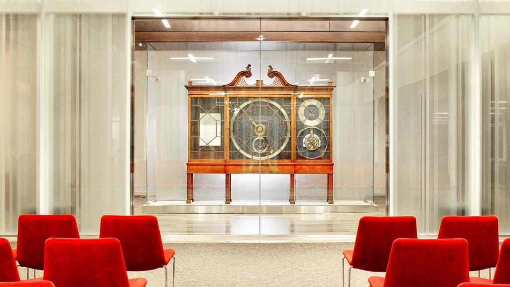 A room with red chairs and a large gold framed window.
