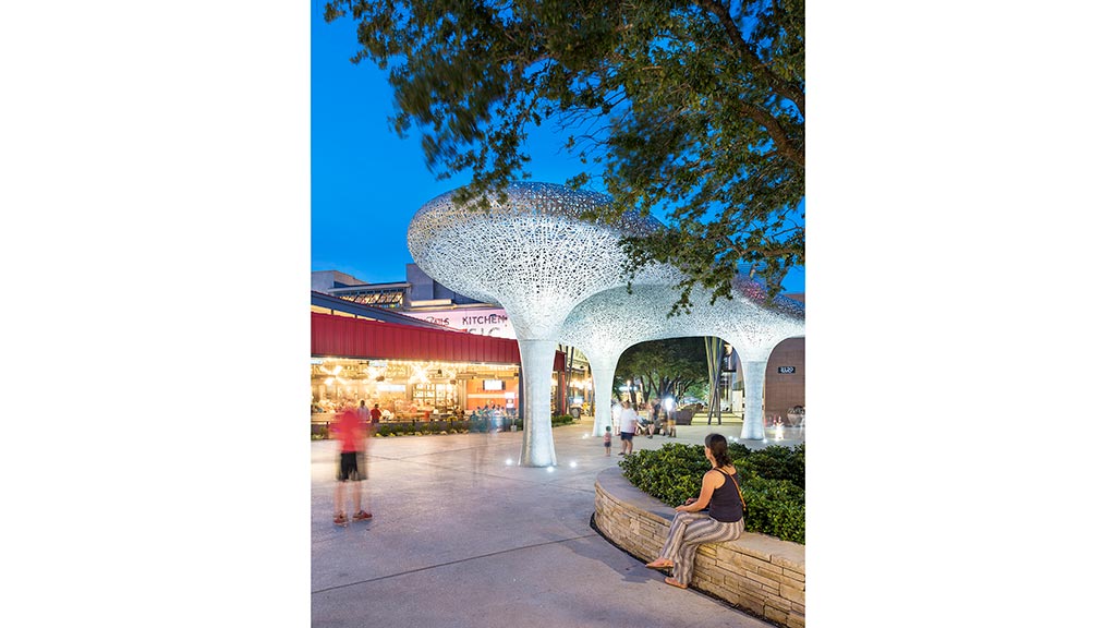 A person sitting on a stone ledge looking at a fountain.