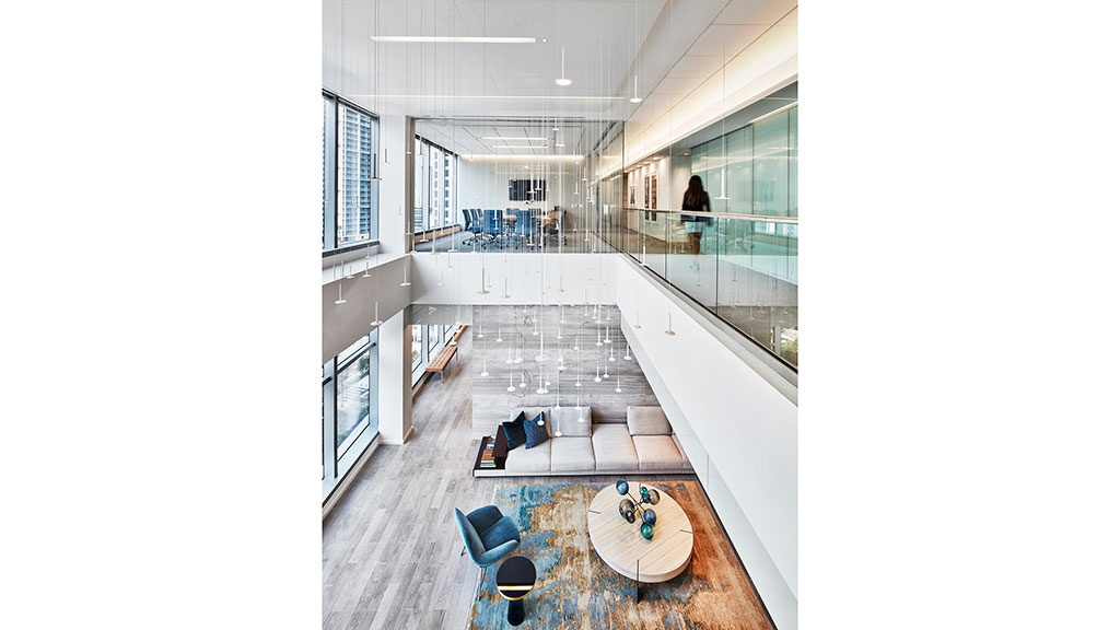 A room with a glass floor and a large white wall with a table and chairs and a person.