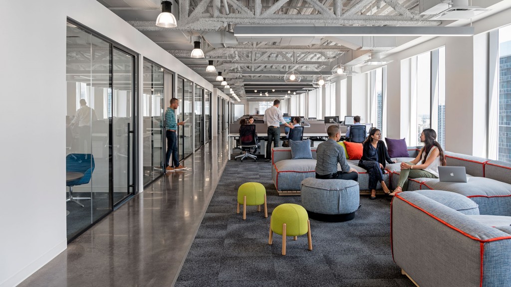 A group of people sitting in a room with chairs and a glass door.