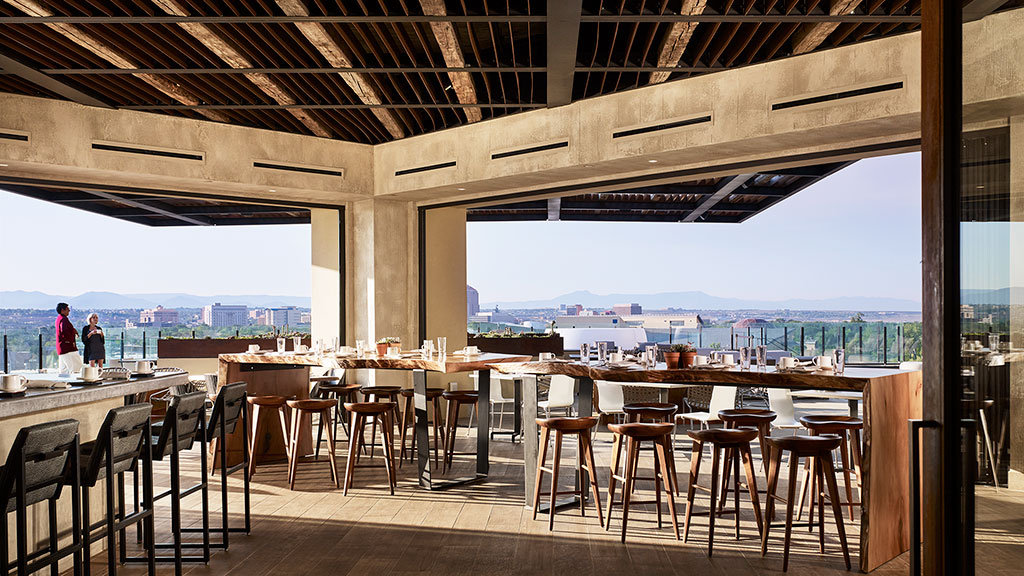 A group of tables and chairs in a room with a view of the city.