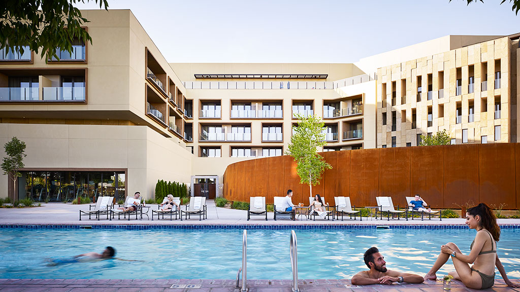 A group of people sitting around a pool in front of a building.