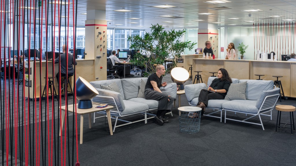 A group of people sitting on couches in a room with a red wall and a red and.