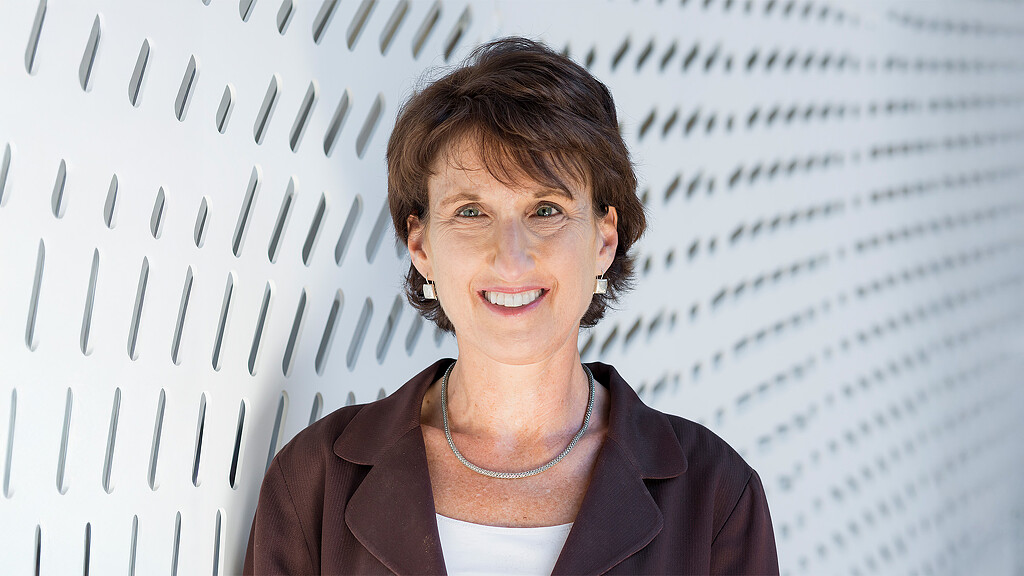 A man smiling in front of a white wall.