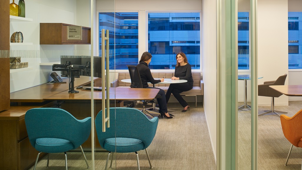 A couple of women sitting at a table in an office.