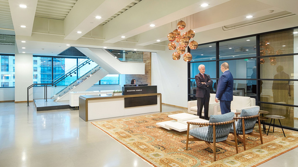 A couple of men in a room with a large glass staircase.