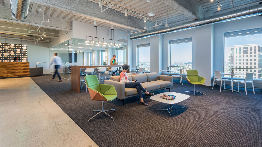 A man and woman sitting on a couch in a room with tables and chairs.