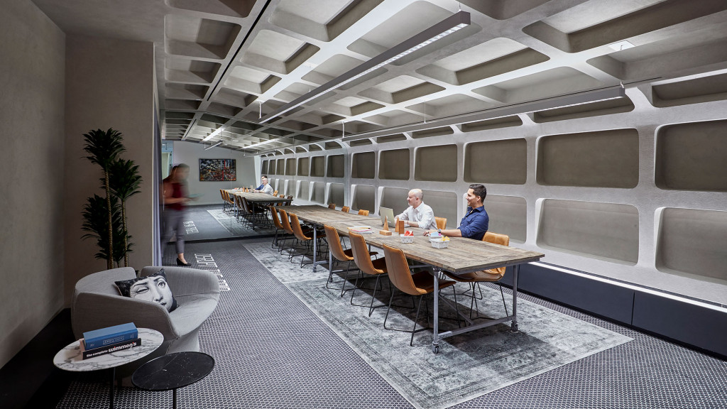 A group of people sitting at a table in a room with white walls.