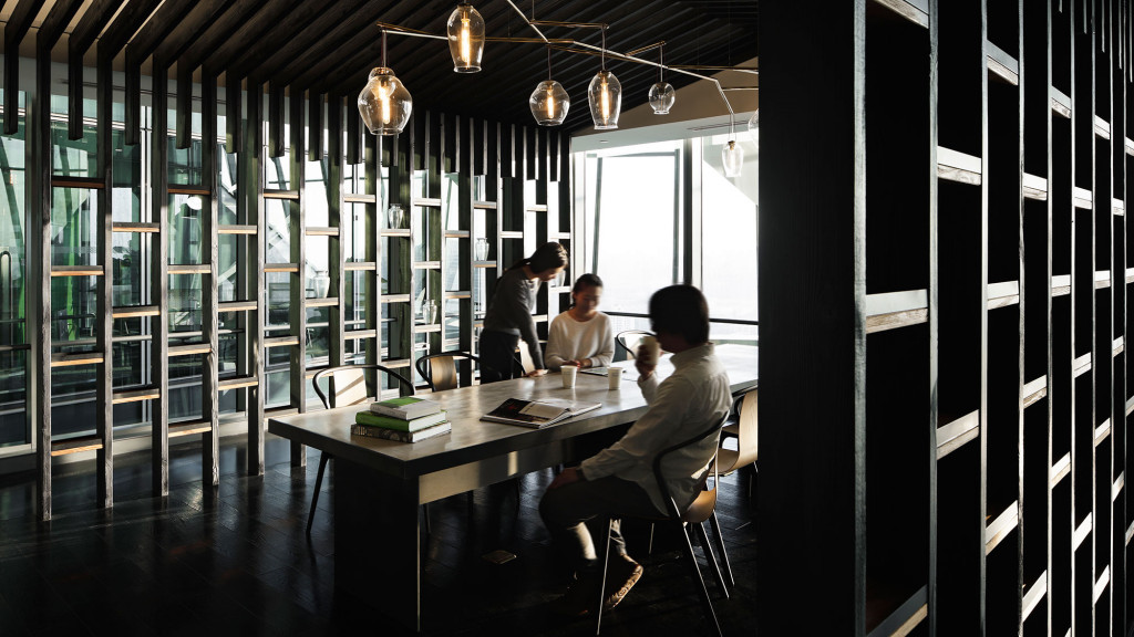 A group of people sitting at a table in a room with glass walls.