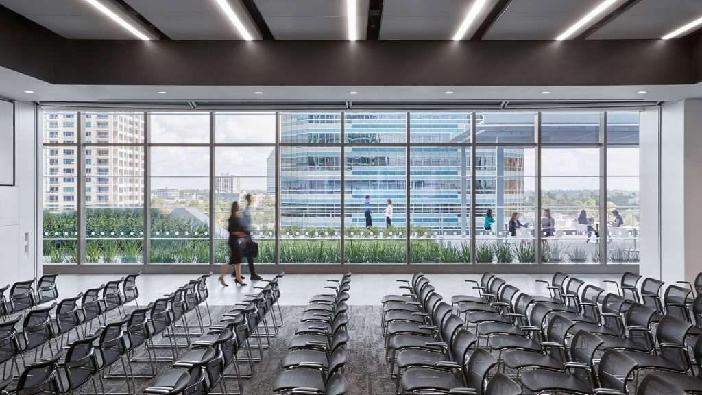 A room with rows of chairs and tables and windows.