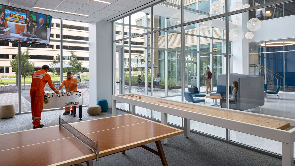 A person in an orange jumpsuit working in a large room.