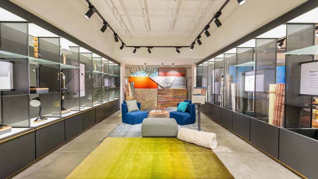 A room with a large glass wall and a large window with a couch and a rug.