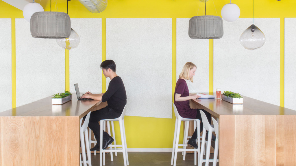 A man and a woman sitting at a table with laptops.