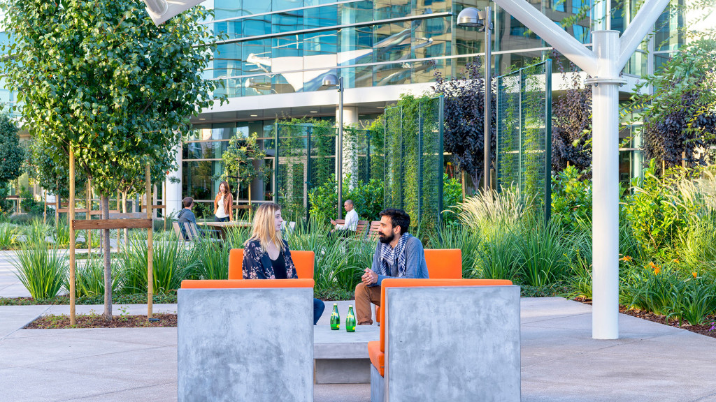 A man and woman sitting on a bench in front of a building.