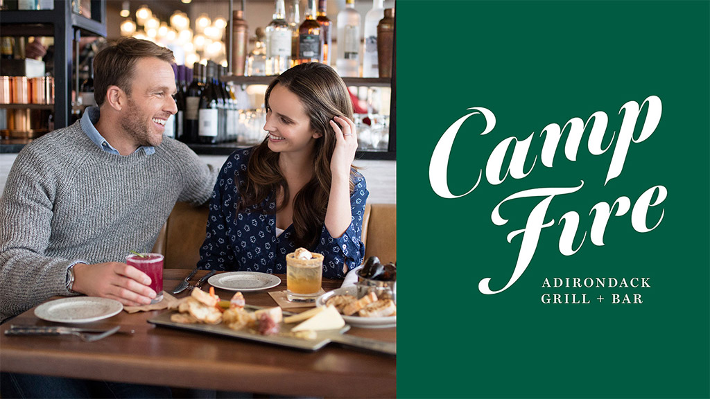 A man and a woman sitting at a table with food and drinks.