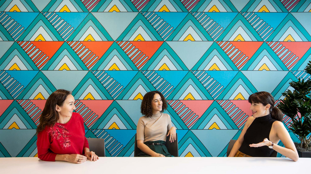 A group of women sitting in front of a flag.