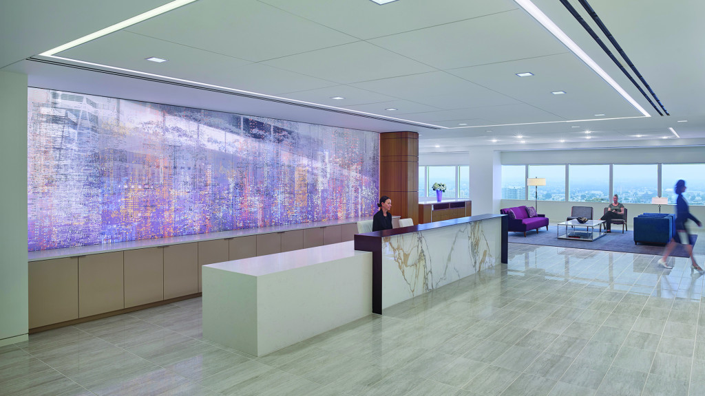 A room with a large screen and people walking around.