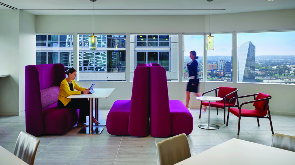 A man and woman in a room with pink chairs and a table.