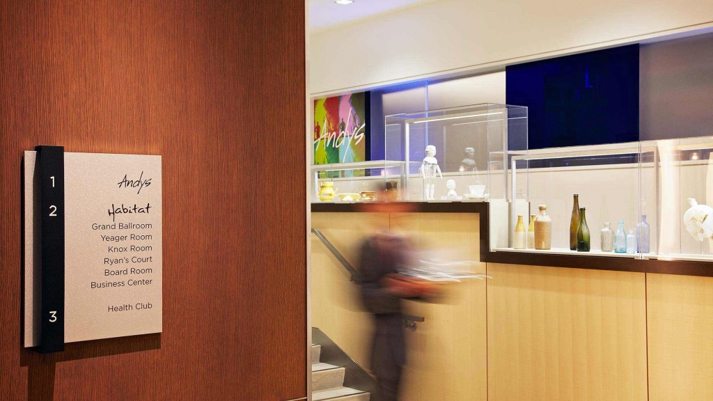 A room with a sign and a counter with bottles and a person standing in it.