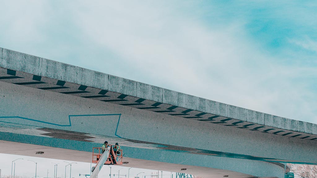 A person on a bike on a bridge over water.