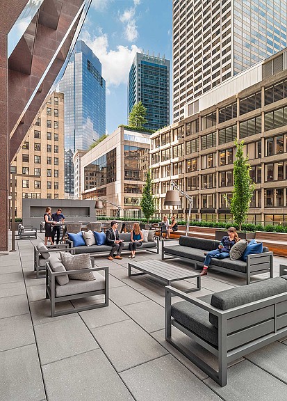 A group of people sitting on benches in a city.