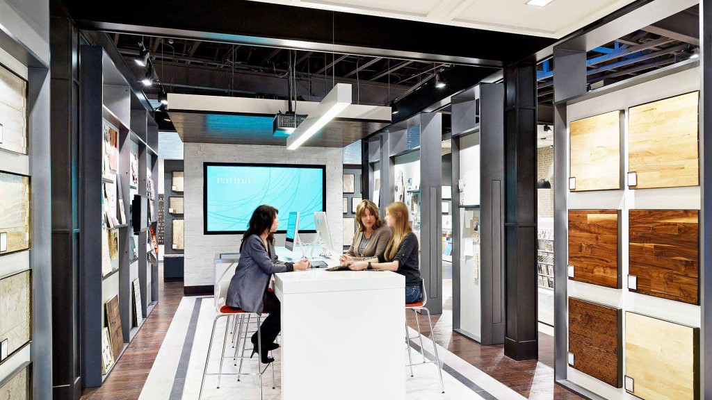 A group of women sitting at a table in a room with a large screen.