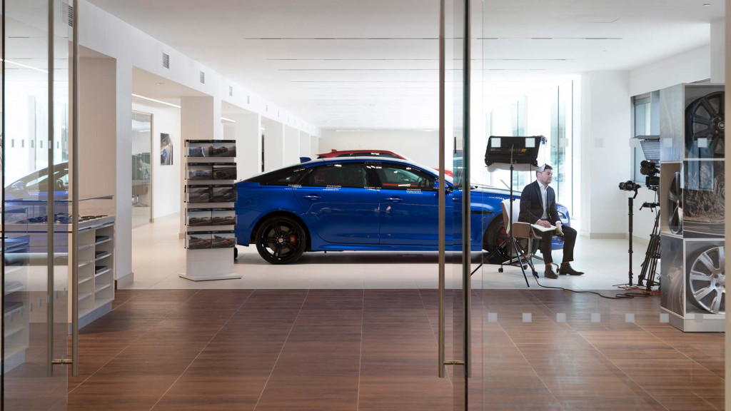 A person sitting in a chair in a room with a blue car.