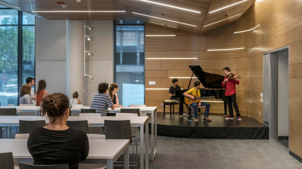 A group of people sitting in a room with a person playing a guitar.