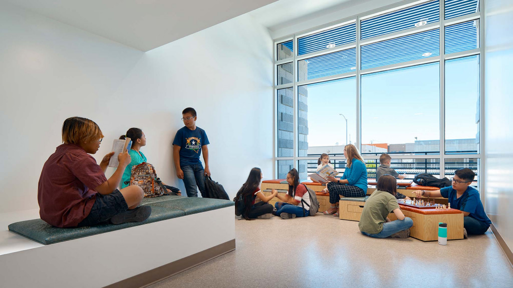 A group of people sitting on a couch in a room with large windows.