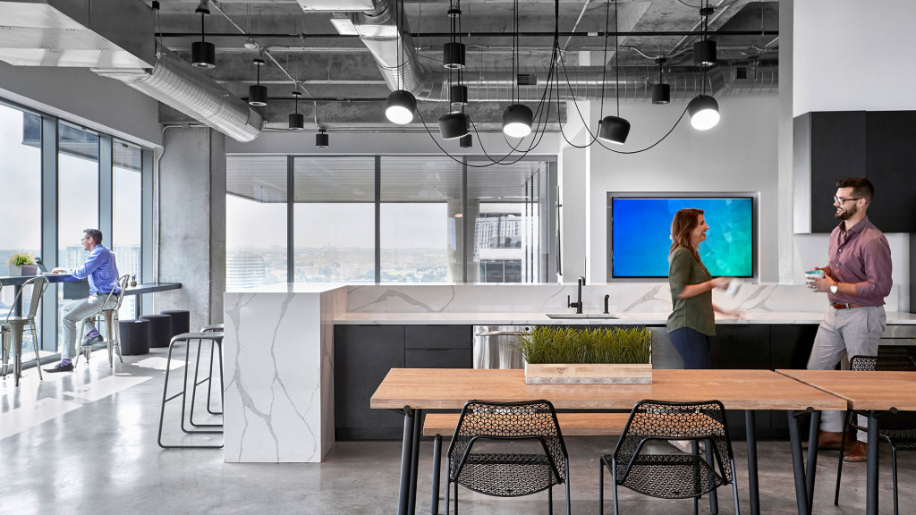 A man and woman standing in a room with a large screen.